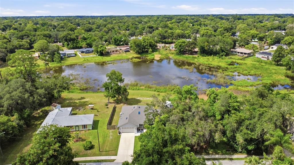 An aerial view shows two houses situated on a grassy lot next to a pond — 120 FLORIDANA ROAD, DEBARY, FL