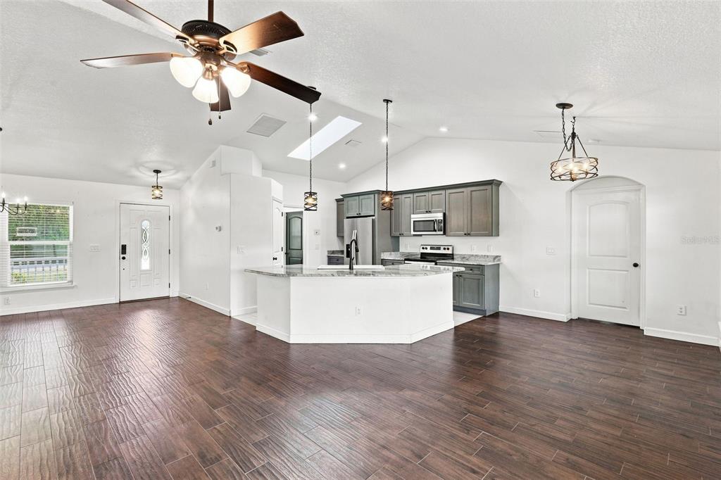 A kitchen with gray cabinets and a white island opens into a large living area — 120 FLORIDANA ROAD, DEBARY, FL