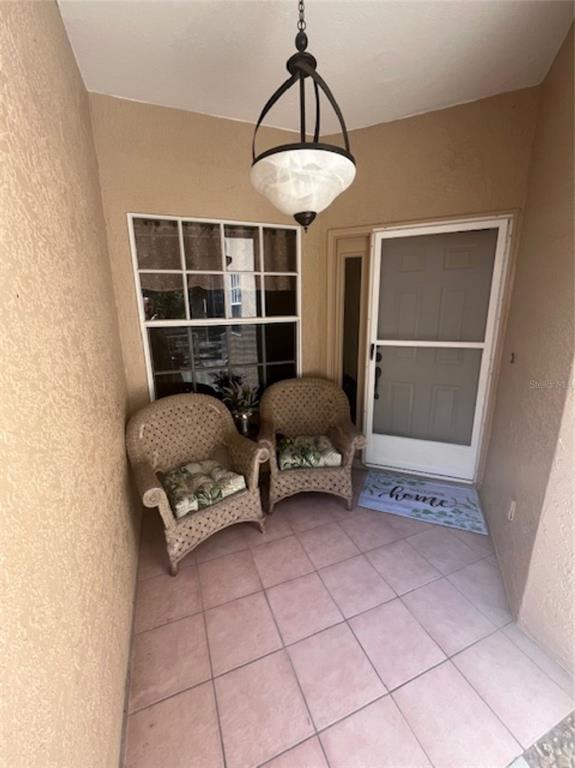 A covered porch features two wicker chairs, a hanging light fixture, and a tiled floor — 3047 OVERLOOK PLACE, CLEARWATER, FL