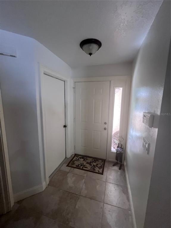 An entryway features a white front door with a sidelight, tile flooring, and a ceiling light — 3047 OVERLOOK PLACE, CLEARWATER, FL