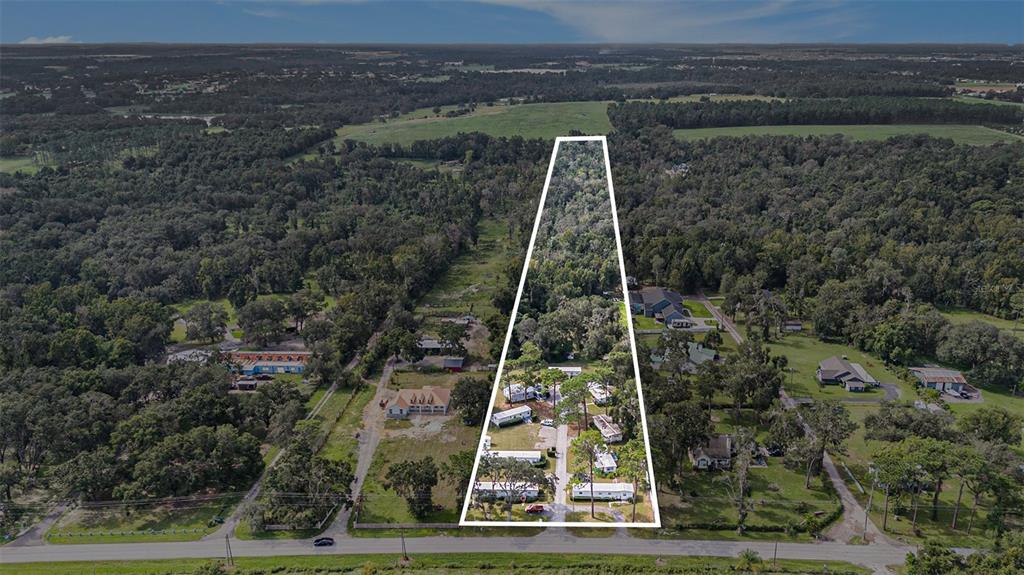 An aerial view shows a trapezoidal property containing several mobile homes surrounded by dense trees — 14638 TREELEAF LANE, DADE CITY, FL