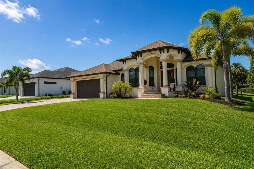 A single-story stucco house with a tiled roof, arched entryway, and palm trees in front — 2197 NITA TERRACE, NORTH PORT, FL