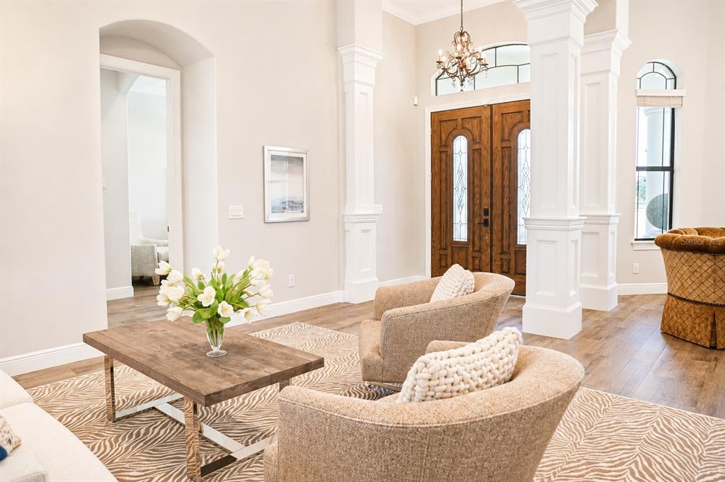 A bright living room features wood floors, a patterned rug, two armchairs, and double doors — 2197 NITA TERRACE, NORTH PORT, FL