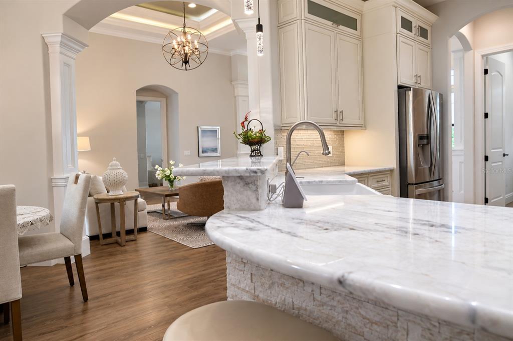 A kitchen with marble countertops and a breakfast bar overlooks a living area — 2197 NITA TERRACE, NORTH PORT, FL