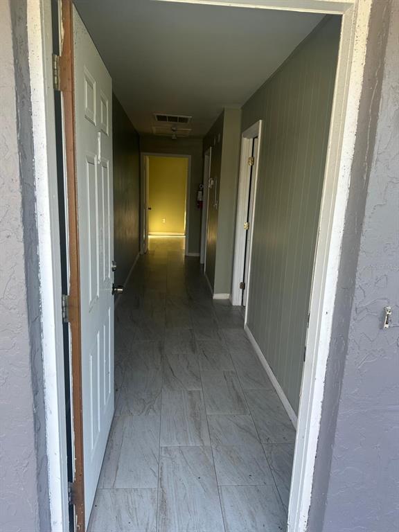 A view through an open door into a hallway with light-colored tile flooring — 214 N CHESTNUT ROAD UNIT 6, LAKELAND, FL