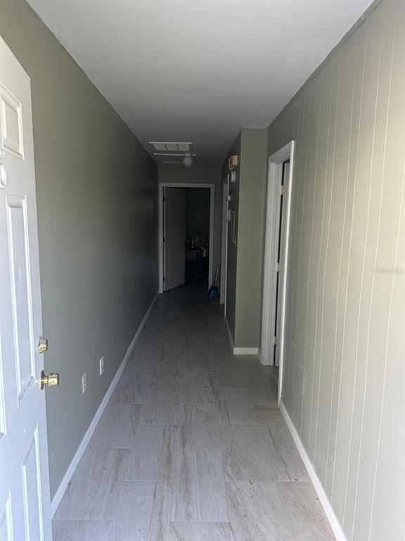 A narrow hallway with light-colored tile flooring leads to a doorway at the far end — 214 N CHESTNUT ROAD UNIT 6, LAKELAND, FL