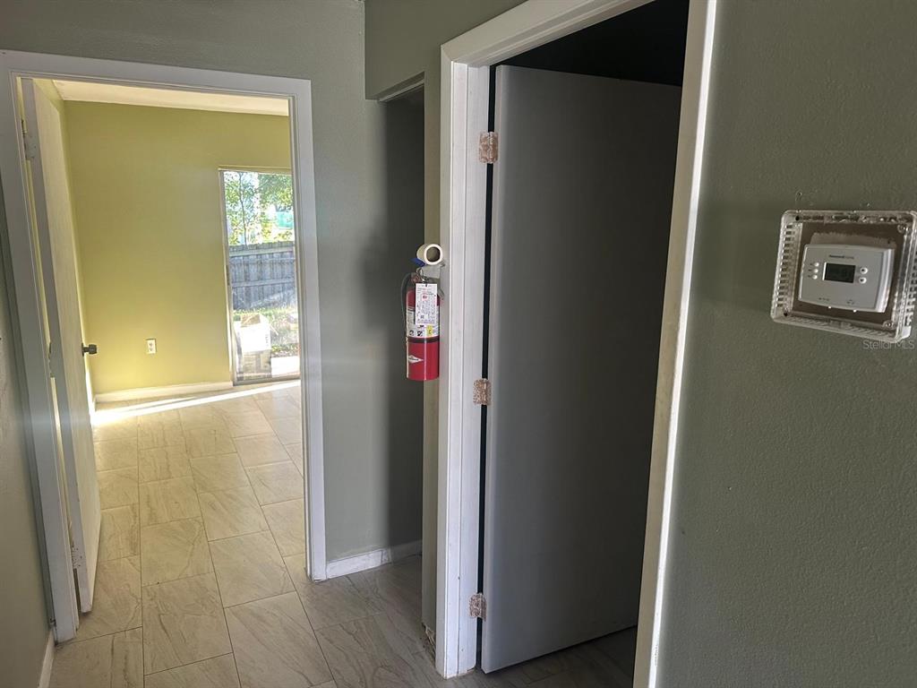 A hallway with tile flooring leads to a room with a sliding glass door — 214 N CHESTNUT ROAD UNIT 6, LAKELAND, FL