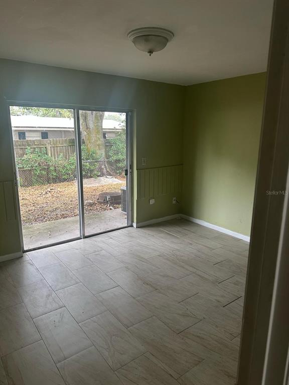 A room with light-colored tile flooring, olive green walls, and a sliding glass door — 214 N CHESTNUT ROAD UNIT 6, LAKELAND, FL