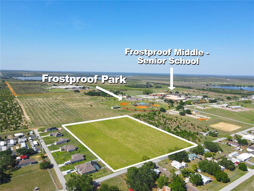 This aerial view shows a vacant rectangular lot near a park and a school — 360 SWINGLE STREET, FROSTPROOF, FL