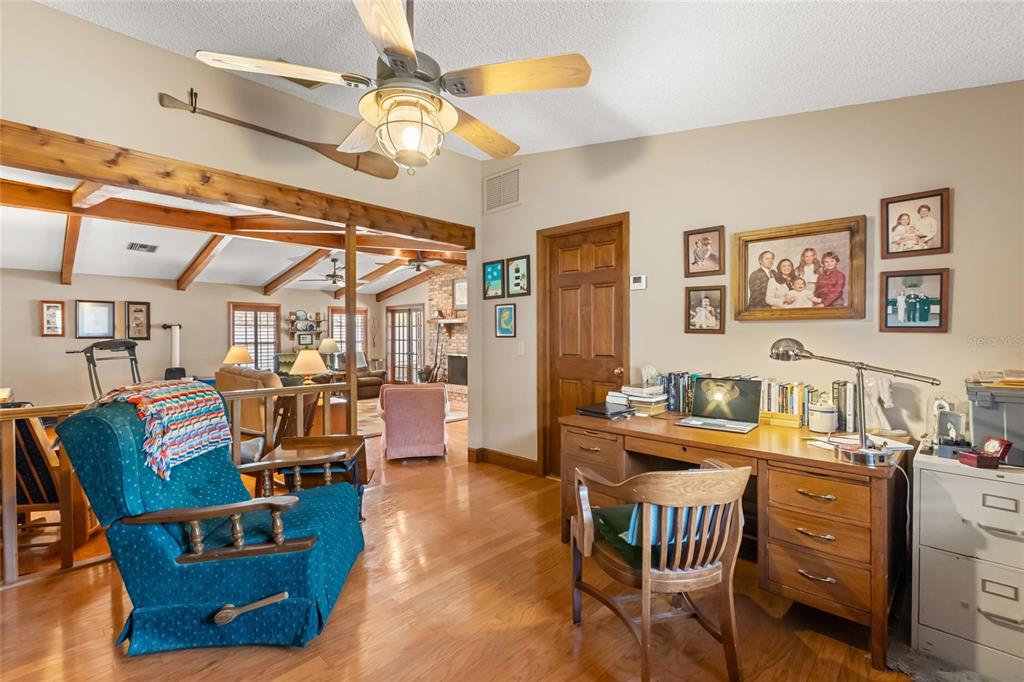 A home office with hardwood floors, a wooden desk, a recliner, and built-in bookshelves — 4925 HOPERITA STREET, ORLANDO, FL