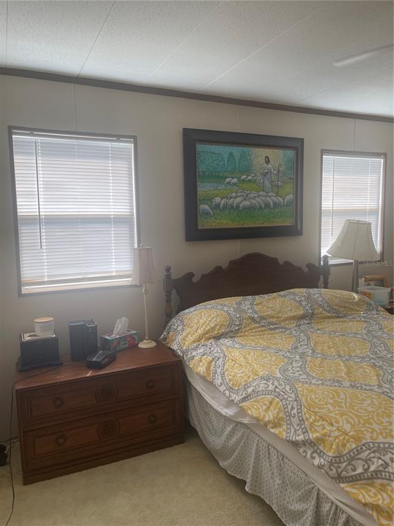 A bedroom features a wooden headboard, a patterned bedspread, and a framed painting on the wall — 501 OAK RIDGE E, LAKELAND, FL