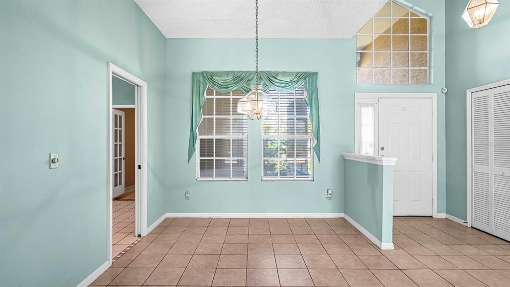A dining area features light blue walls, tile flooring, a chandelier, and a front door — 14648 POTANOW TRAIL, ORLANDO, FL