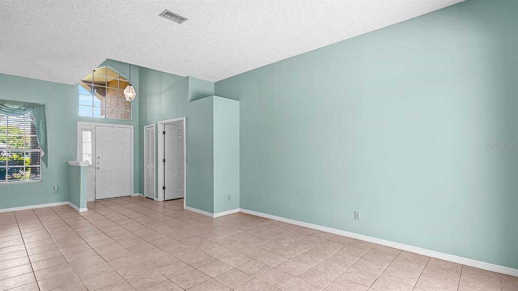 A spacious room with light-colored tile flooring, high ceilings, and light blue walls — 14648 POTANOW TRAIL, ORLANDO, FL