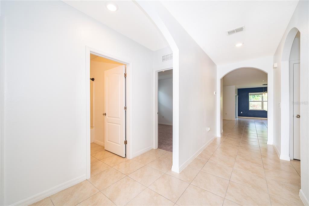 A tiled hallway leads to an arched entryway with a view of a blue-walled room — 239 LAZIO CIRCLE, DEBARY, FL
