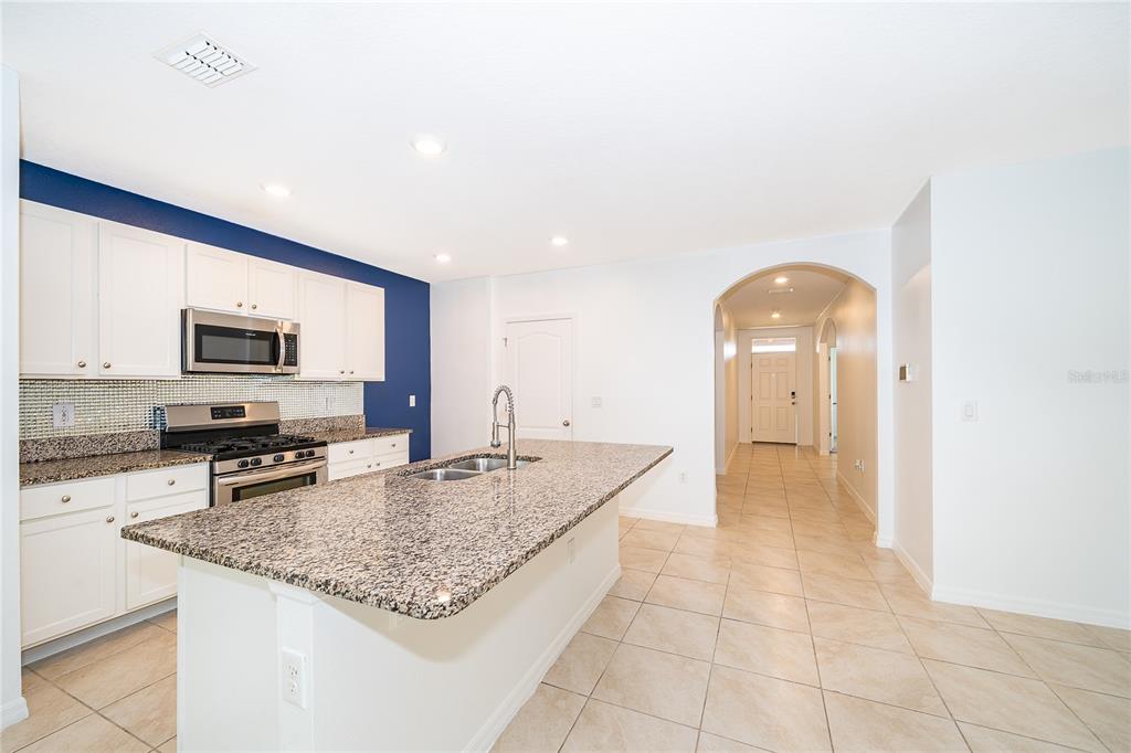 A kitchen features white cabinets, granite countertops, a central island, and a blue accent wall — 239 LAZIO CIRCLE, DEBARY, FL