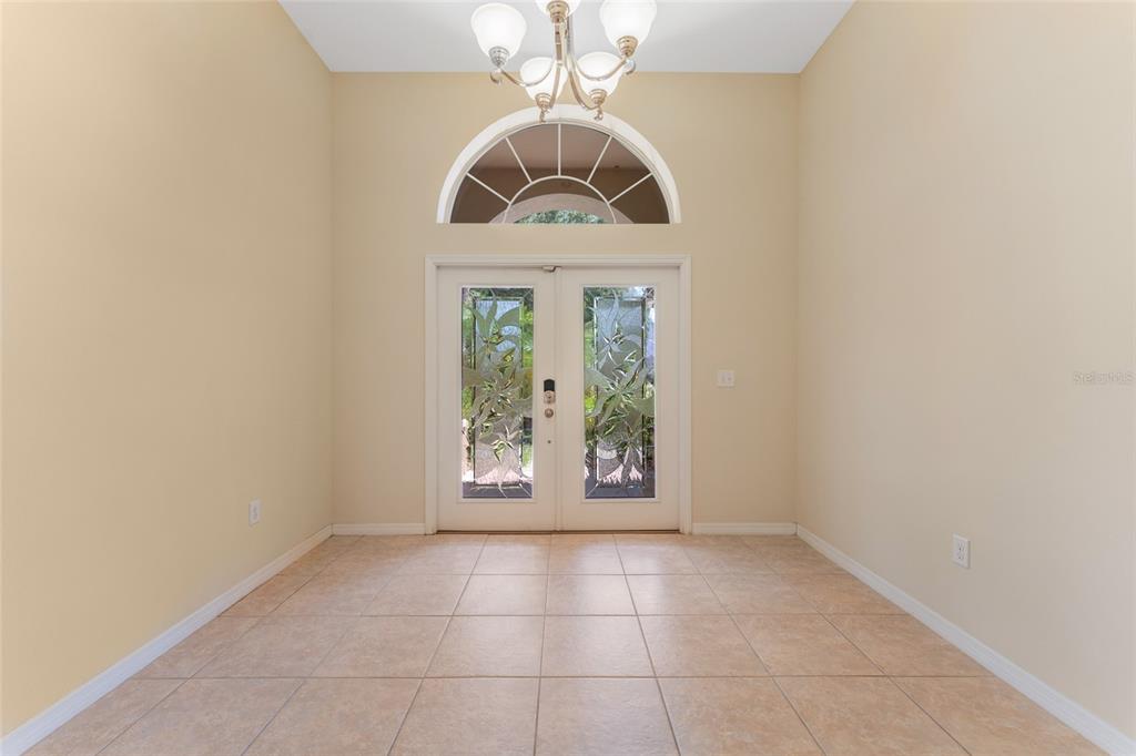 An entryway features tile flooring, a chandelier, and double glass doors with an arched transom window — 2637 YUKON CLIFF DRIVE, RUSKIN, FL