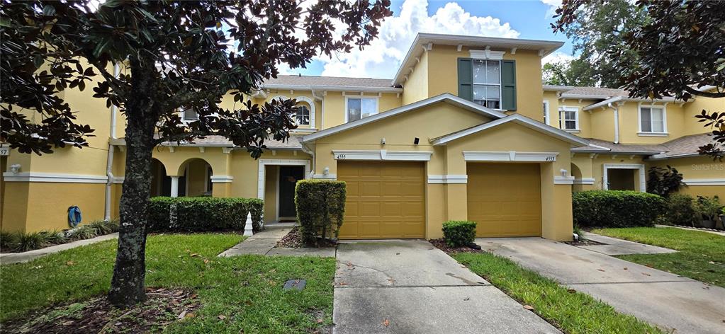 A two-story yellow townhouse features two garage doors and a small front lawn — 4555 LIMERICK DRIVE, TAMPA, FL