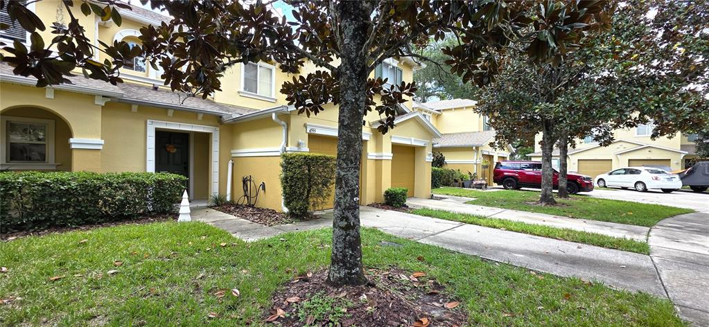 A yellow two-story townhouse features a front entrance, a garage, and a landscaped yard — 4555 LIMERICK DRIVE, TAMPA, FL