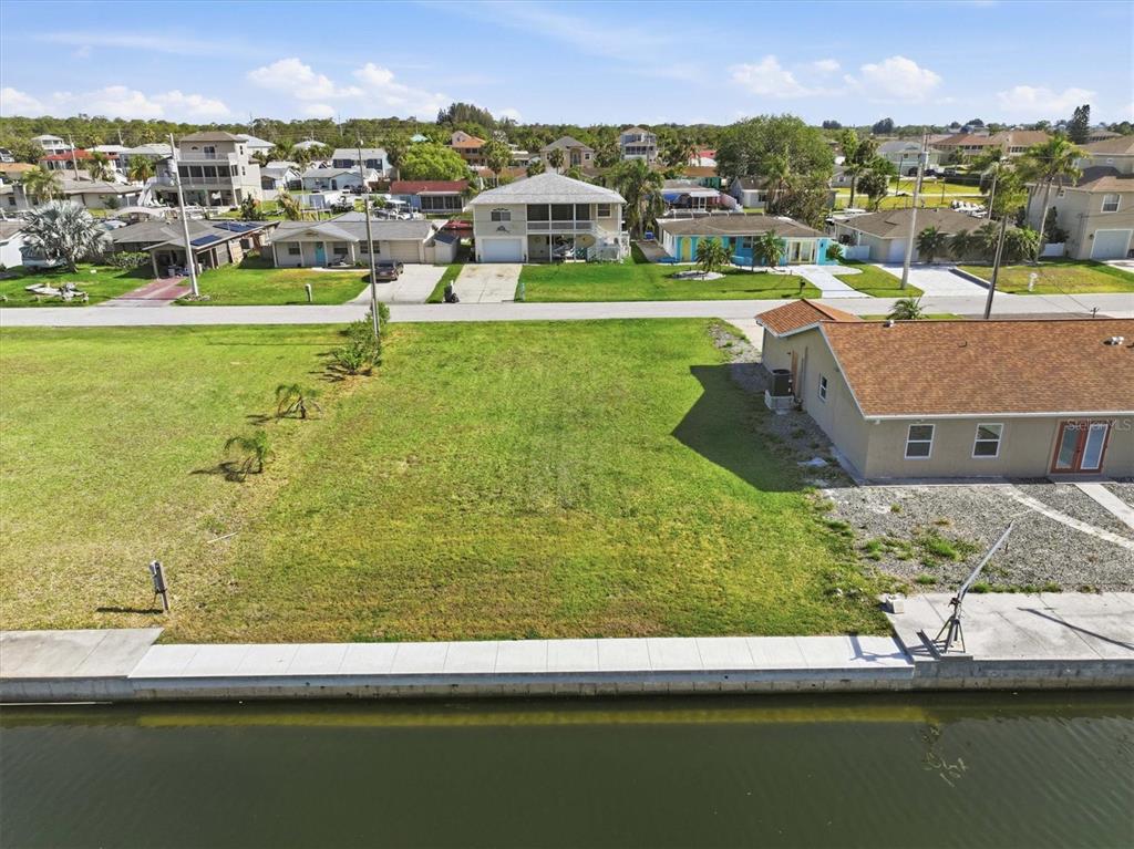 An aerial view shows a vacant waterfront lot next to a house with a seawall — 7429 HATTERAS DRIVE, HUDSON, FL