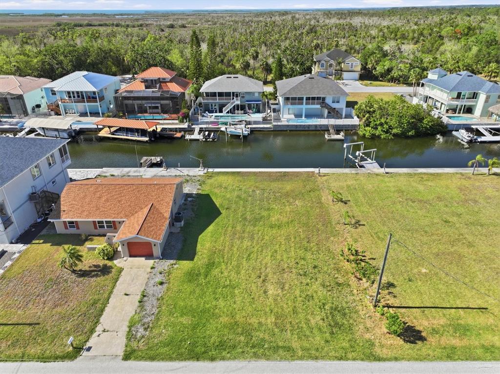 An aerial view shows a vacant waterfront lot next to a house with a garage — 7429 HATTERAS DRIVE, HUDSON, FL