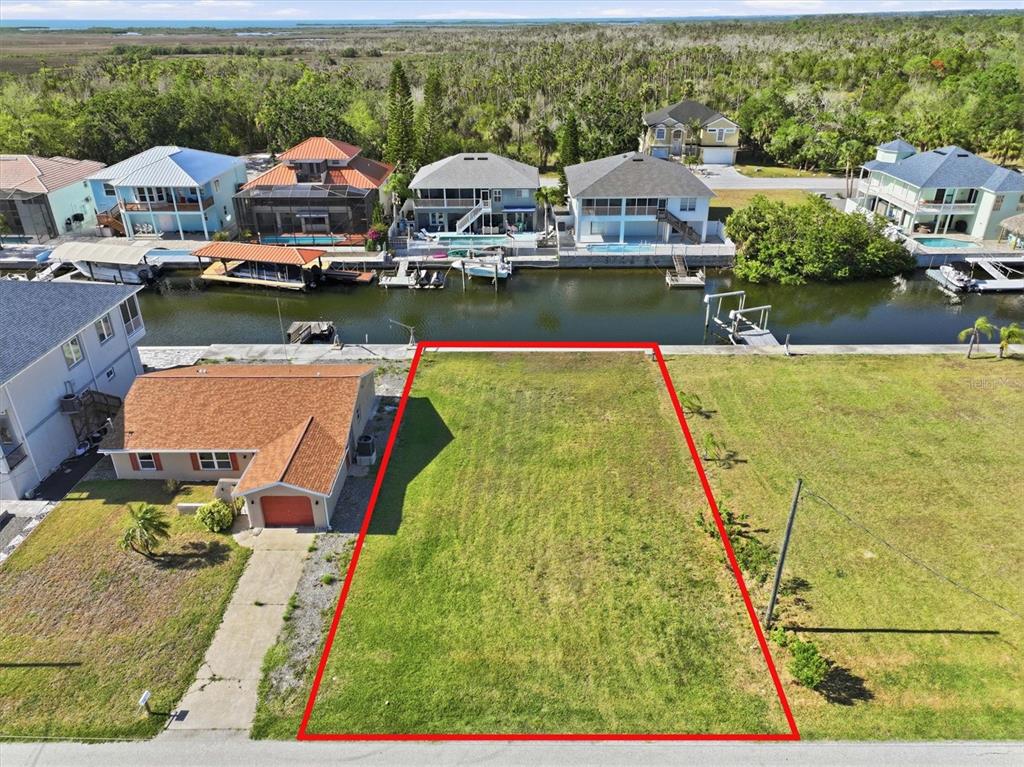 An aerial view shows a vacant waterfront lot outlined in red next to a house — 7429 HATTERAS DRIVE, HUDSON, FL