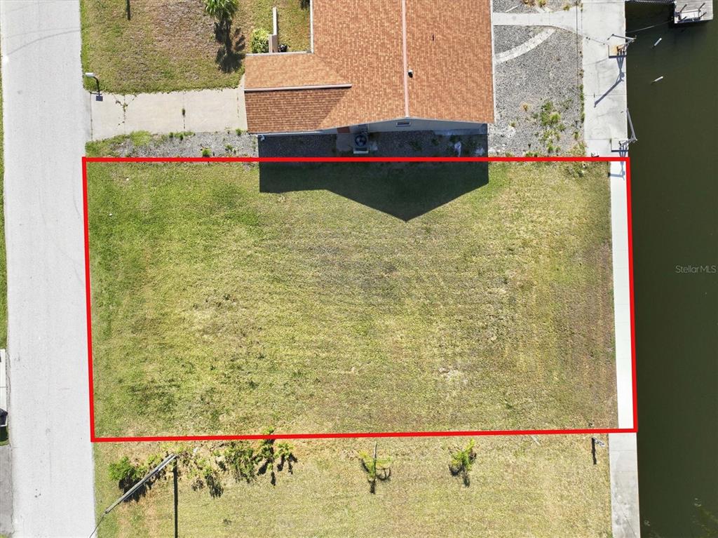 An aerial view shows a rectangular vacant lot bordered by a road and a canal — 7429 HATTERAS DRIVE, HUDSON, FL