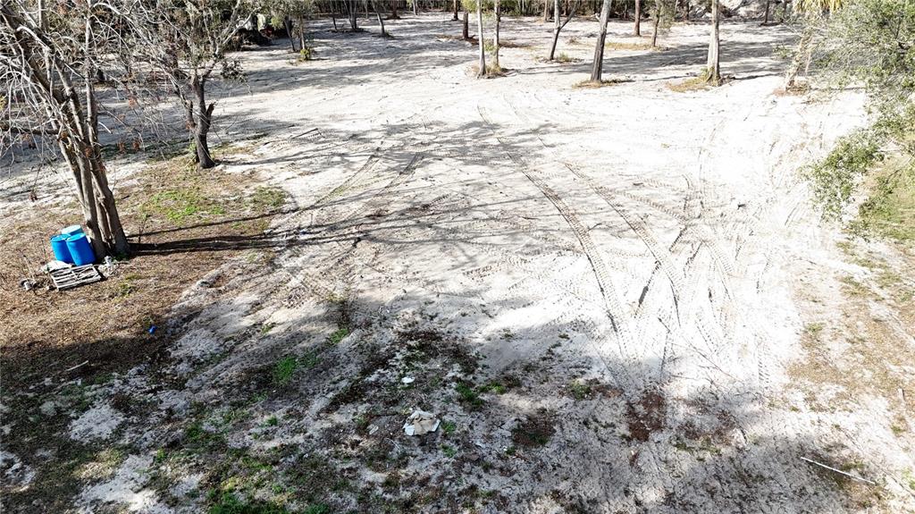 An aerial view shows a sandy, cleared lot with scattered trees and tire tracks — 12510 ROBINHOOD ROAD, HUDSON, FL