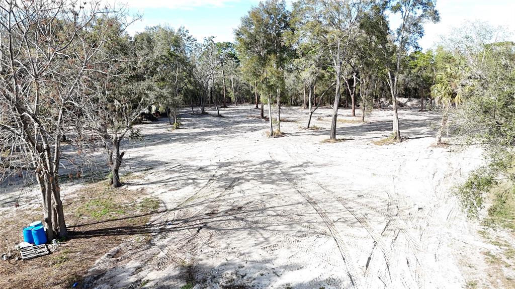 An aerial view shows a cleared, sandy lot with scattered trees and tire tracks — 12510 ROBINHOOD ROAD, HUDSON, FL