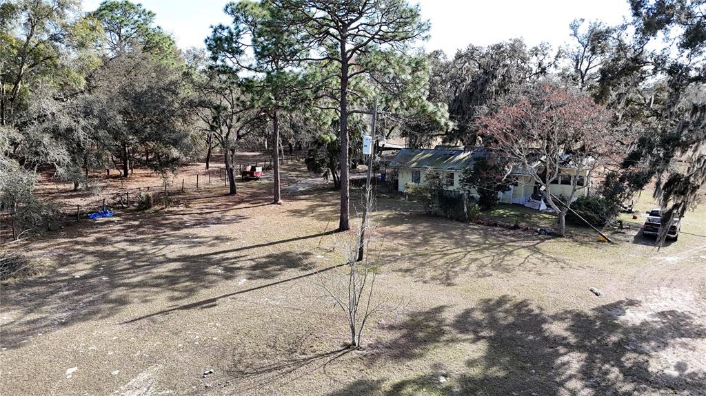 An aerial view shows a single-story house situated on a large, tree-filled grassy lot — 12510 ROBINHOOD ROAD, HUDSON, FL
