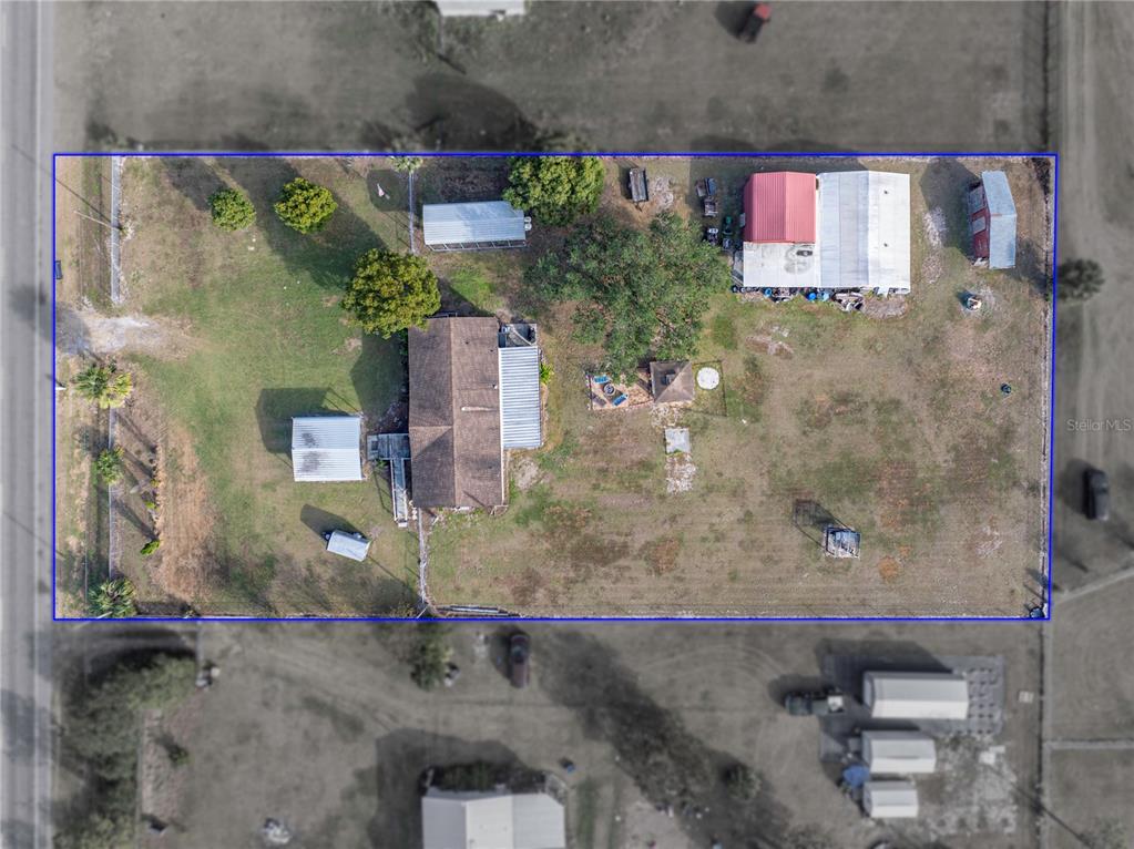 This aerial view shows a residential property with a house, several outbuildings, and trees — 11404 LITHIA PINECREST ROAD, LITHIA, FL