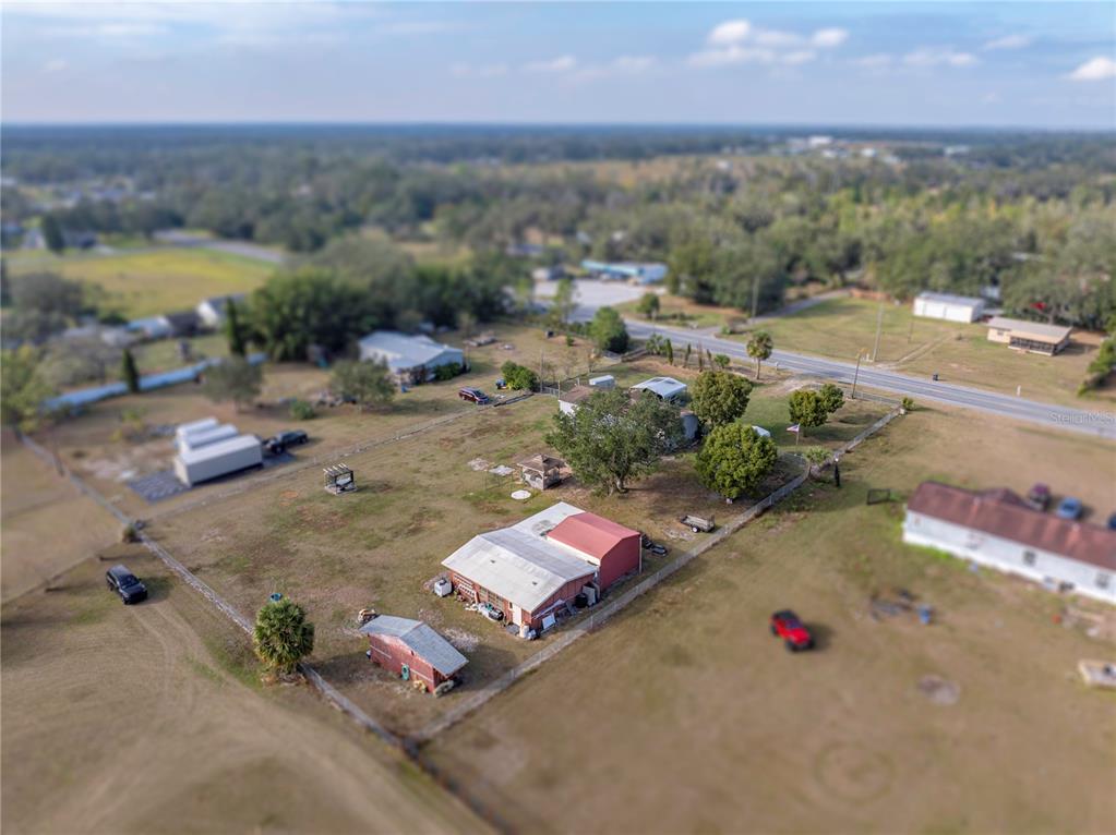 An aerial view shows a rural property with several outbuildings, a house, and fenced yards — 11404 LITHIA PINECREST ROAD, LITHIA, FL