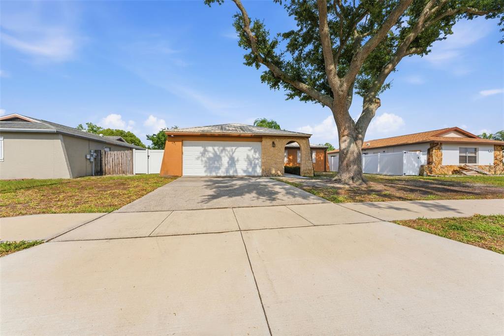 A single-story house with a stone-accented entryway, a two-car garage, and a sunset sky — 611 TANGERINE DRIVE, OLDSMAR, FL
