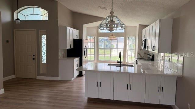 A kitchen features white cabinets, a central island with a sink, and light wood flooring — 1619 ELMSTEAD COURT, ORLANDO, FL