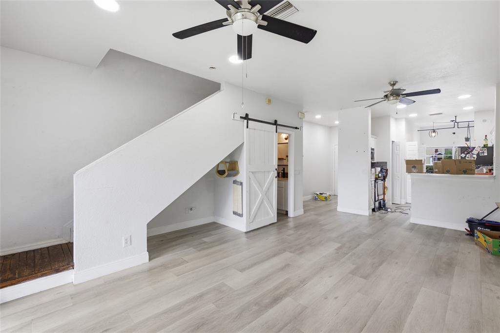 A living room with light wood-look flooring, a staircase, and a white sliding barn door — 11009 WINTER CREST DRIVE, RIVERVIEW, FL