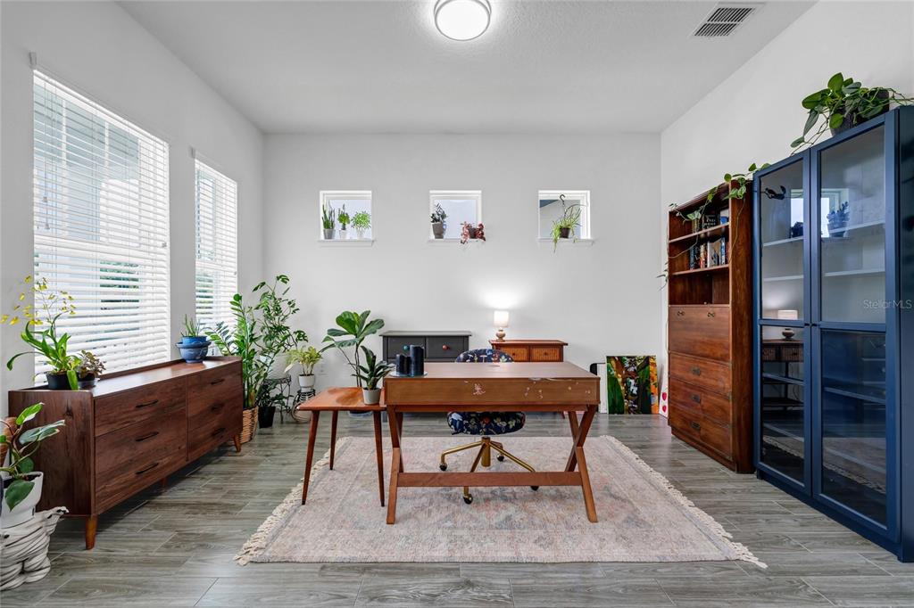 A home office features a wooden desk, a blue cabinet, and several potted plants — 12929 WESTSIDE VILLAGE LOOP, WINDERMERE, FL
