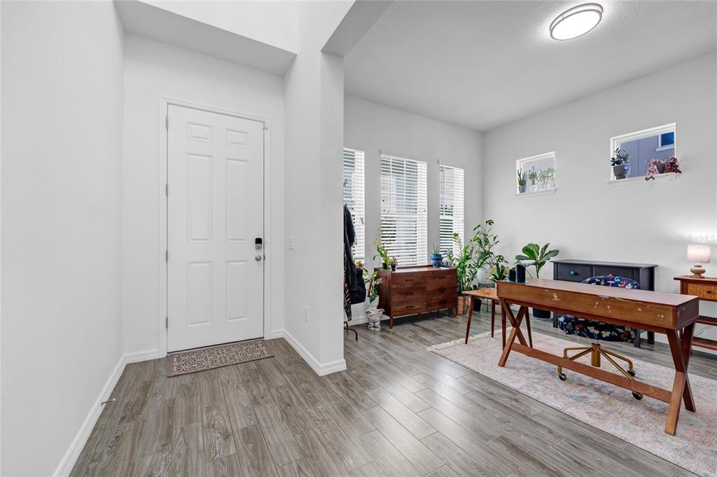 A bright entryway with wood-look tile flooring leads into a home office space — 12929 WESTSIDE VILLAGE LOOP, WINDERMERE, FL