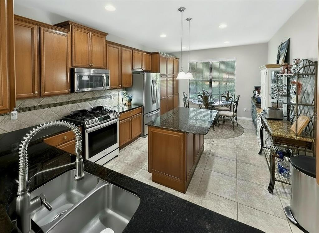 A kitchen with wood cabinets, granite countertops, stainless steel appliances, and a central island — 442 DEL SOL AVE, DAVENPORT, FL