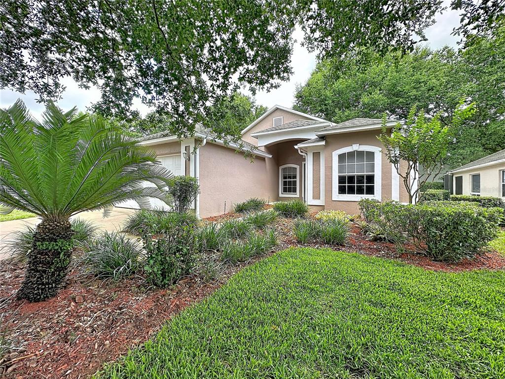 A single-story house with a tan stucco exterior, a front-facing garage, and landscaped front yard — 3675 EVERSHOLT STREET, CLERMONT, FL