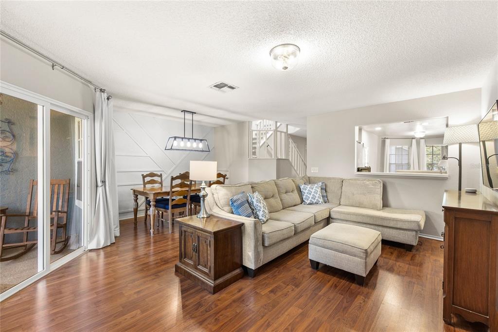 A living room with wood flooring, a sectional sofa, and an adjacent dining area — 1482 CREEKSIDE CIRCLE, WINTER SPRINGS, FL