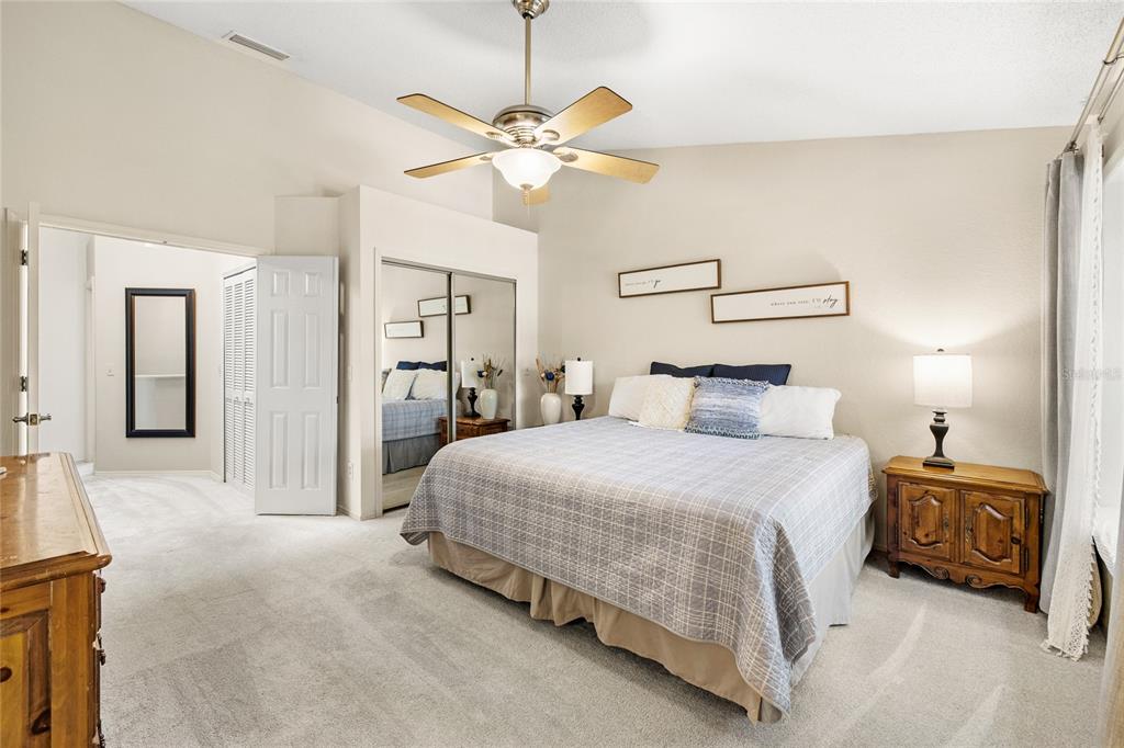 A bedroom features a king bed, mirrored closet doors, a ceiling fan, and carpeted flooring — 1482 CREEKSIDE CIRCLE, WINTER SPRINGS, FL