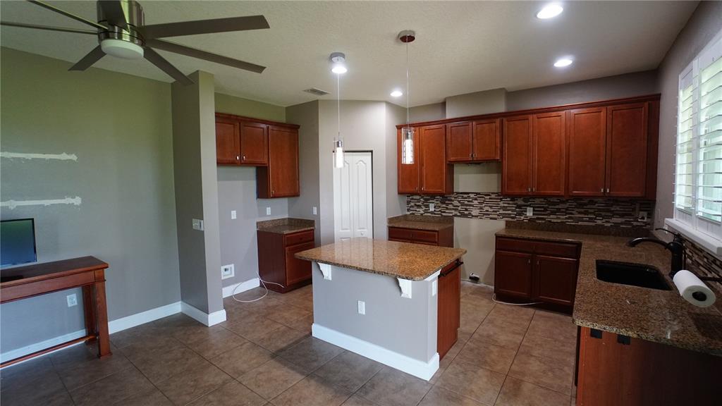 A kitchen features cherry wood cabinets, granite countertops, a center island, and tile flooring — 222 STAR SHELL DRIVE, APOLLO BEACH, FL