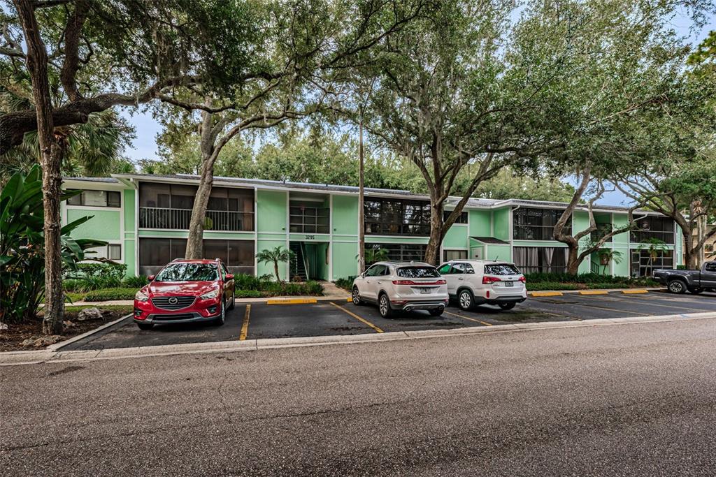 A two-story light green apartment building with a parking lot in front — 3295 FOX CHASE CIRCLE N UNIT 107, PALM HARBOR, FL