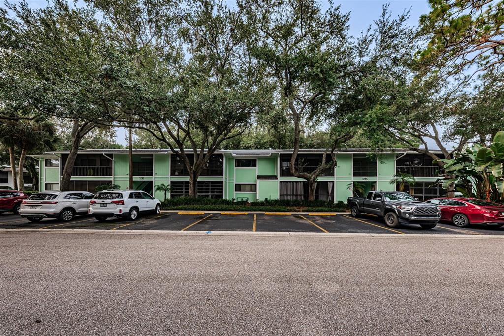 A two-story light green apartment building with a parking lot in front — 3295 FOX CHASE CIRCLE N UNIT 107, PALM HARBOR, FL