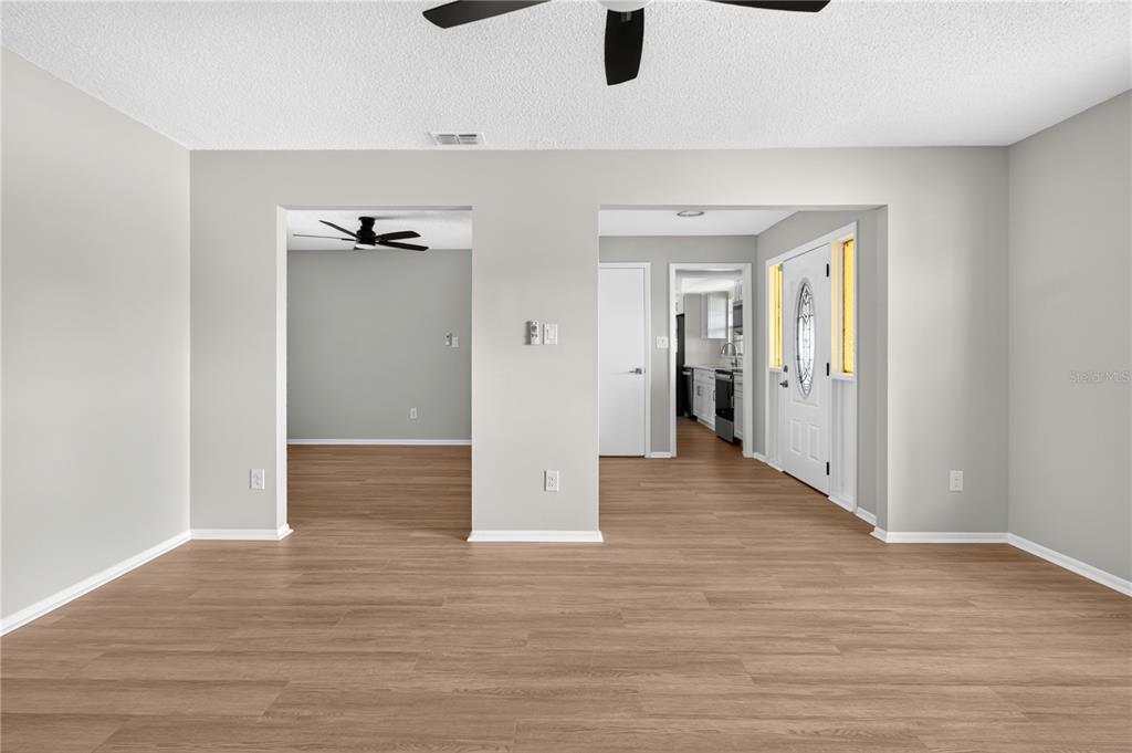 A modern kitchen features white cabinetry, stainless steel appliances, and light wood-look flooring — 1442 CANTERBURY CIRCLE, CASSELBERRY, FL