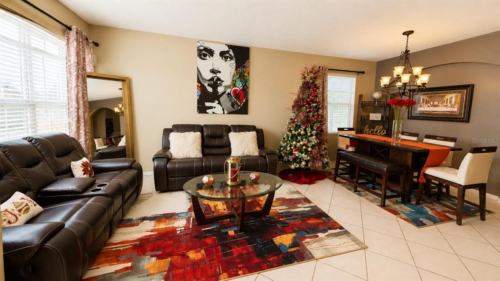 A living and dining room features dark leather furniture, a colorful rug, and a Christmas tree — 8703 FORT SHEA AVENUE, ORLANDO, FL