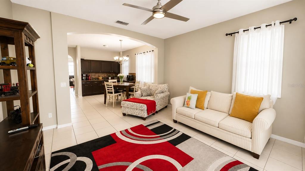 A living room with a patterned rug and sofa opens into a dining area and kitchen — 8703 FORT SHEA AVENUE, ORLANDO, FL