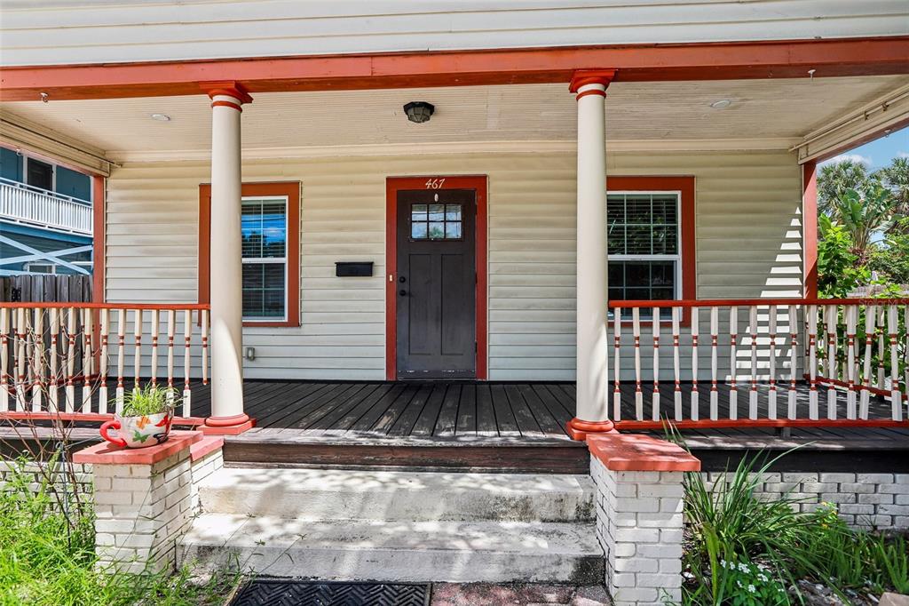 A front porch with a wooden deck, white railings, and a dark door with a window — 467 9TH AVENUE N, ST PETERSBURG, FL