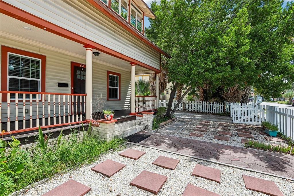 A house with a front porch, red trim, and a gravel yard with stone pavers — 467 9TH AVENUE N, ST PETERSBURG, FL