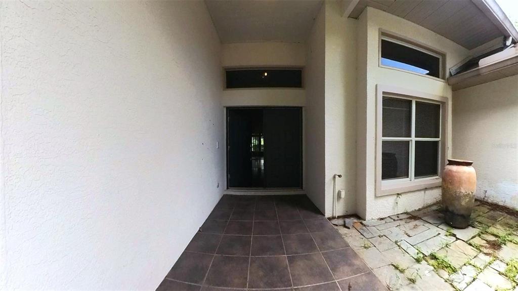 A covered patio features dark tile flooring, a sliding glass door, and a stone-paved area — 2535 ARDON AVENUE, ORLANDO, FL