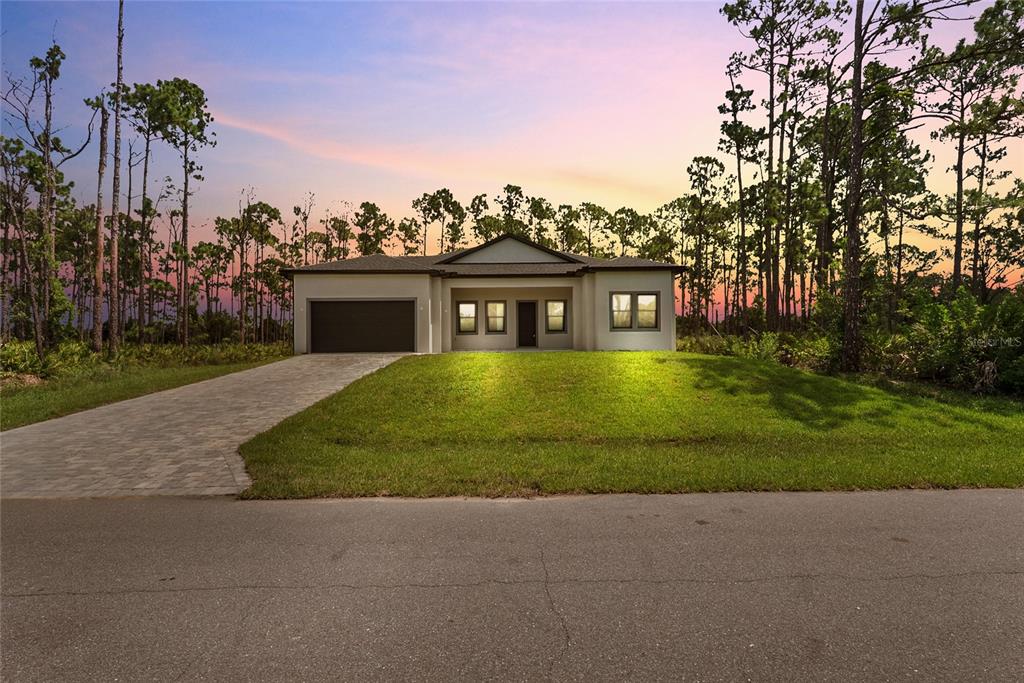 A single-story house with a paved driveway and garage sits in a wooded area — 372 MATSON LANE, PORT CHARLOTTE, FL